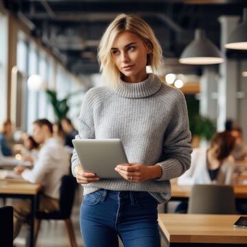 A beautiful girl stands in an office, she holds a laptop in her hand. Generative Ai.