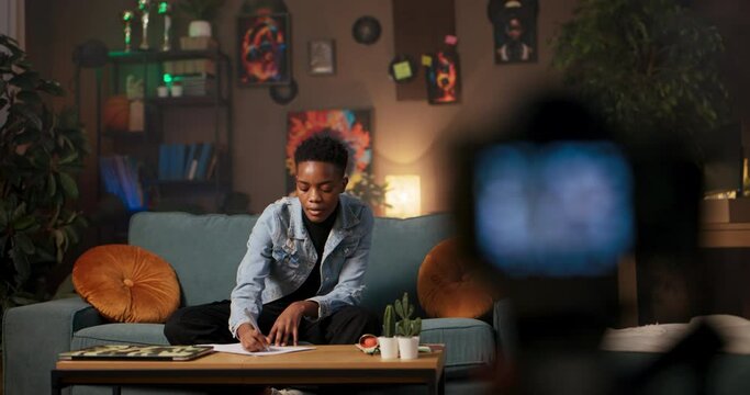 Legal advocate or paralegal African woman in the living room talks to the camera while holding papers, discussing legal matters and preparing documents for legal cases.