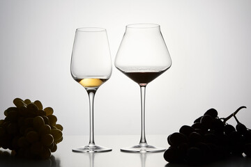 Red, white wine in stemware with dark grapes.