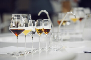 Various alcoholic beverages in glasses in white table in wine room. Sommelier school, professional certification, winemaking association.