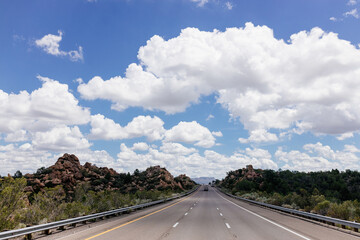 Beautiful summer landscape with highway among rocky mountains and blue sky with fluffy clouds on a summer day. Roadscape in New Mexico near Albuquerque, USA