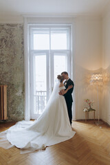 The first meeting of the groom in a black suit and the bride in a white wedding dress with a bouquet in the interior of a photo studio on a white and black background