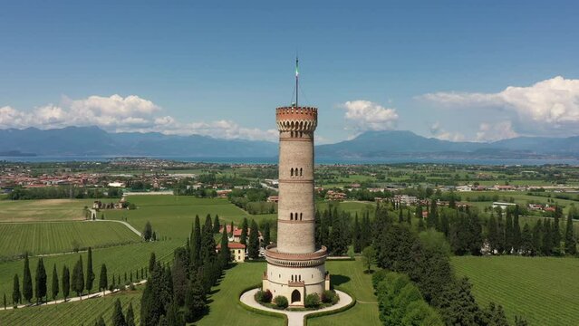 Vertical flight up along the Tower of San Martino della Battaglia with Lake Garda and mountains in the background, Italy.