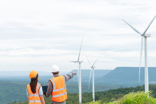 Male and female engineers working on a wind farm atop a hill or mountain in the rural. Progressive ideal for the future production of renewable, sustainable energy.