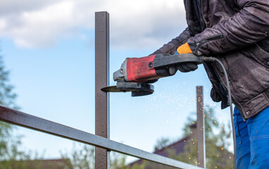 A worker is cutting metal to install a fence