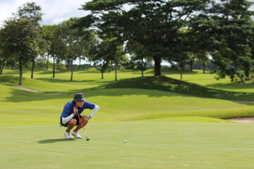 Obraz premium Golfers putting golf balls on the green amid the warm sunshine in the morning. Concept of Outdoor activities and Outdoor sports, Concept of Golfer and Lifestyle. 