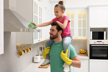 Spring cleaning. Father and daughter tidying up in kitchen together