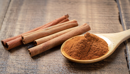 Close up cinnamon sticks and cinnamon powder in wooden spoon on wooden table background, healthy spice concept