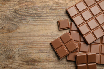 Delicious milk chocolate on wooden table, flat lay. Space for text