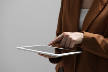 Naklejka premium Closeup view of woman using modern tablet on grey background