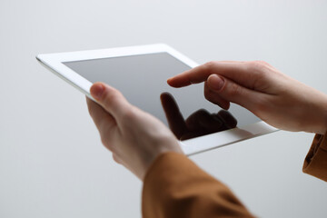 Closeup view of woman using modern tablet on light grey background