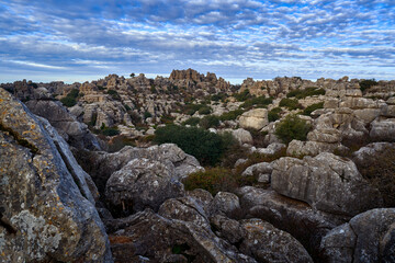 Spain rock mountain landscape. El Torcal de Antequera, nature reserve in Sierra del Torcal range, province of Málaga in Spain. Grey rock landscape with blue sky and white clouds. Traveling in Europe.