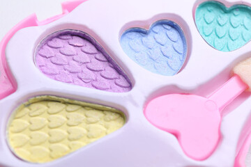 Decorative cosmetics for kids. Eye shadow palette with applicator as background, closeup