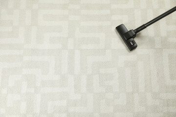 Hoovering white carpet with modern vacuum cleaner, top view. Space for text