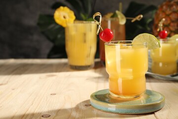 Tasty pineapple cocktail with cherry and lime on wooden table. Space for text