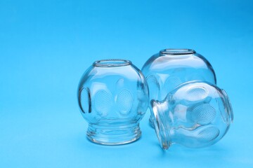 Glass cups on light blue background, closeup with space for text. Cupping therapy