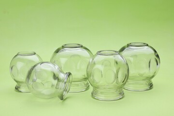 Glass cups on light green background. Cupping therapy