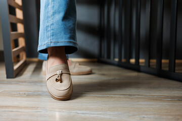 Close-up of female legs in jeans and beige loafers made of genuine leather.