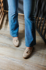 Close-up of female legs in jeans and beige loafers made of genuine leather.