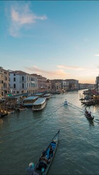 Sunset timelapse of Grand canal from the Rialto Bridge in Venice, Italy, Europe. Time-lapse night illumination Venetian city lights and famous romantic gondolas. Travel Destination. Vertical video.