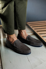 Male legs close-up in jeans and beige genuine leather moccasins.