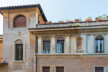 Old shabby plaster facade with a window renaissance ornament and metal bars