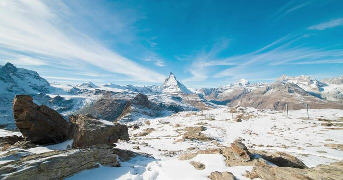 Panoramic nature landscape timelapse of Mount Matterhorn covering with white snow and clouds movement on mountains peak in a sunny day at Zermatt, Switzerland. Famous travel ski resort in Swiss alps.