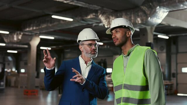 Two Employees at Depository Discussing. Engineer Explaining Tasks to Contractor. Logistic Workers Creating Plan. People at Background of Shelves Full of Goods. Distribution, Business Export Concept
