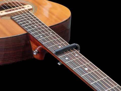 Capo on the Acoustic guitar neck , capro made from aluminium, Selective focus at capo, black background