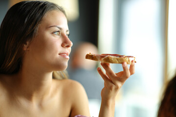 Woman contemplating holding toasted bread with ham