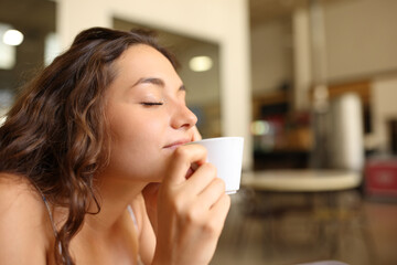 Woman enjoying coffee aroma in a restaurant - obrazy, fototapety, plakaty