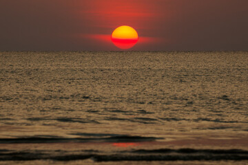 Big sun setting down over the sea.