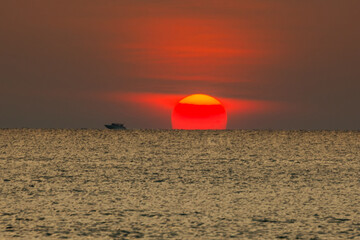 Big sun setting down over the sea.