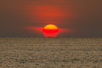 Big sun setting down over the sea.