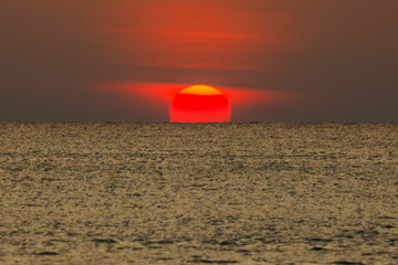 Big sun setting down over the sea.
