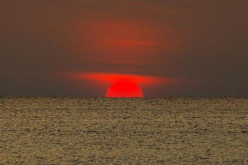 Big sun setting down over the sea.
