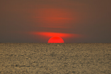 Big sun setting down over the sea.