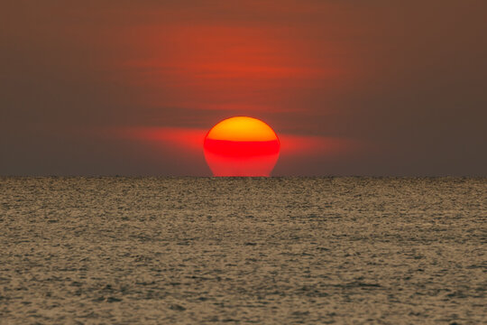 Big sun setting down over the sea.