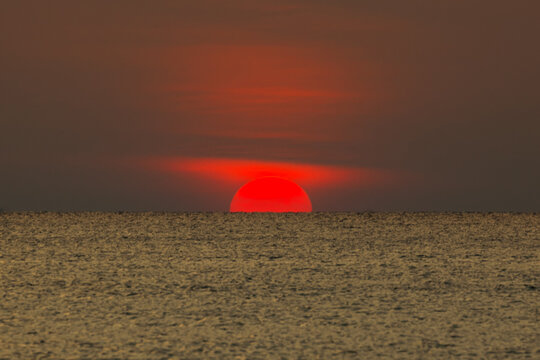 Big sun setting down over the sea.