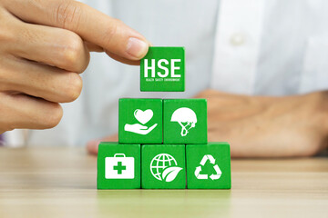 HSE - health safety environment concept.Hand holding wooden cube block with HSE icon.Work safety...