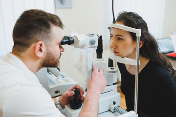 Examination of vision on modern ophthalmological equipment. Eye examination of a woman at an ophthalmologist's appointment using microscopes. Vision treatment at an ophthalmologist appointment