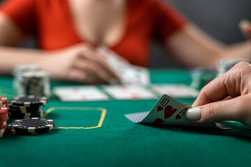 beautiful young girl sits at a poker table with cards in her hands and a player opposite. poker game of chance