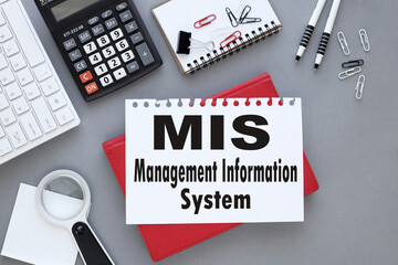 MIS management information system symbol. white sheet of paper with text. on a red notepad on a gray background near a white keyboard.
