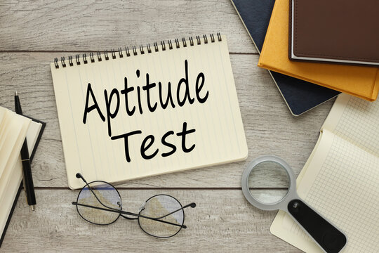 APTITUDE TEST text on notepad with spring. near glasses. Legal and law concept.