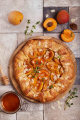 Galette with apricots, brown sugar, honey, and almond petals. Delicious homemade open sweet pie tart with honey and seasonal fruits.