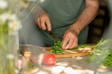 Man chopping green leafy vegetables at home