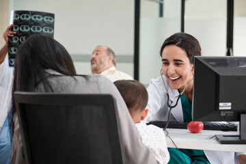 Young female pediatric doctor teases little Asian boy before medical examination at outpatient...