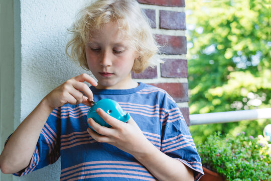 Boy putting coin in piggy bank