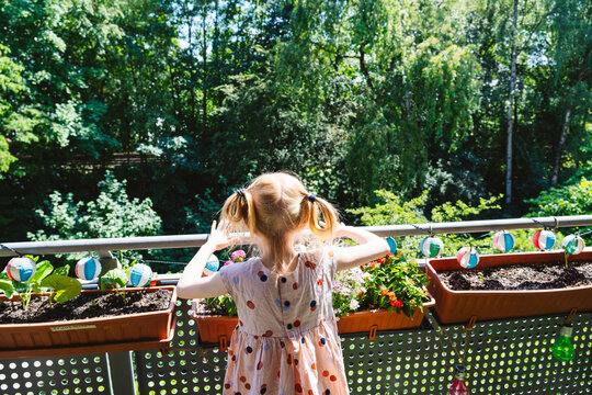 Girl standing near plants in balcony at sunny day