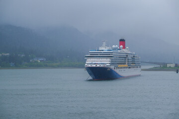Modern cruiseship cruise ship liner Luminiosa anchored in Juneau bay, Alaska during heavy rain and...